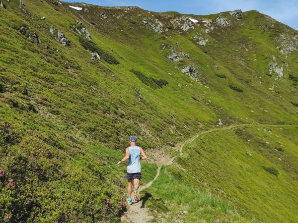 Trailrunner auf Bergpfad mit Panoramablick in den Alpen